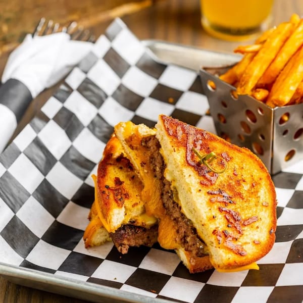 Rookies Sports Bar & Grill's grilled cheese burger with fries on checkered paper.